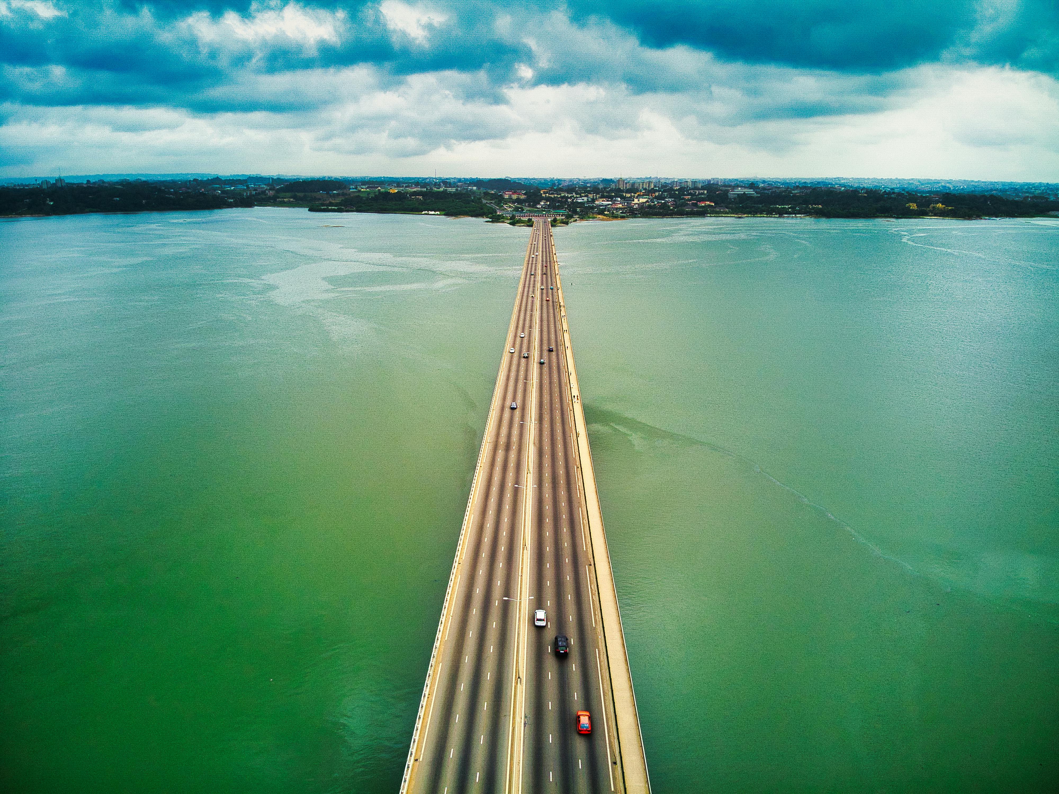 Aerial view of highway bridge crossing turquoise water leading to African city