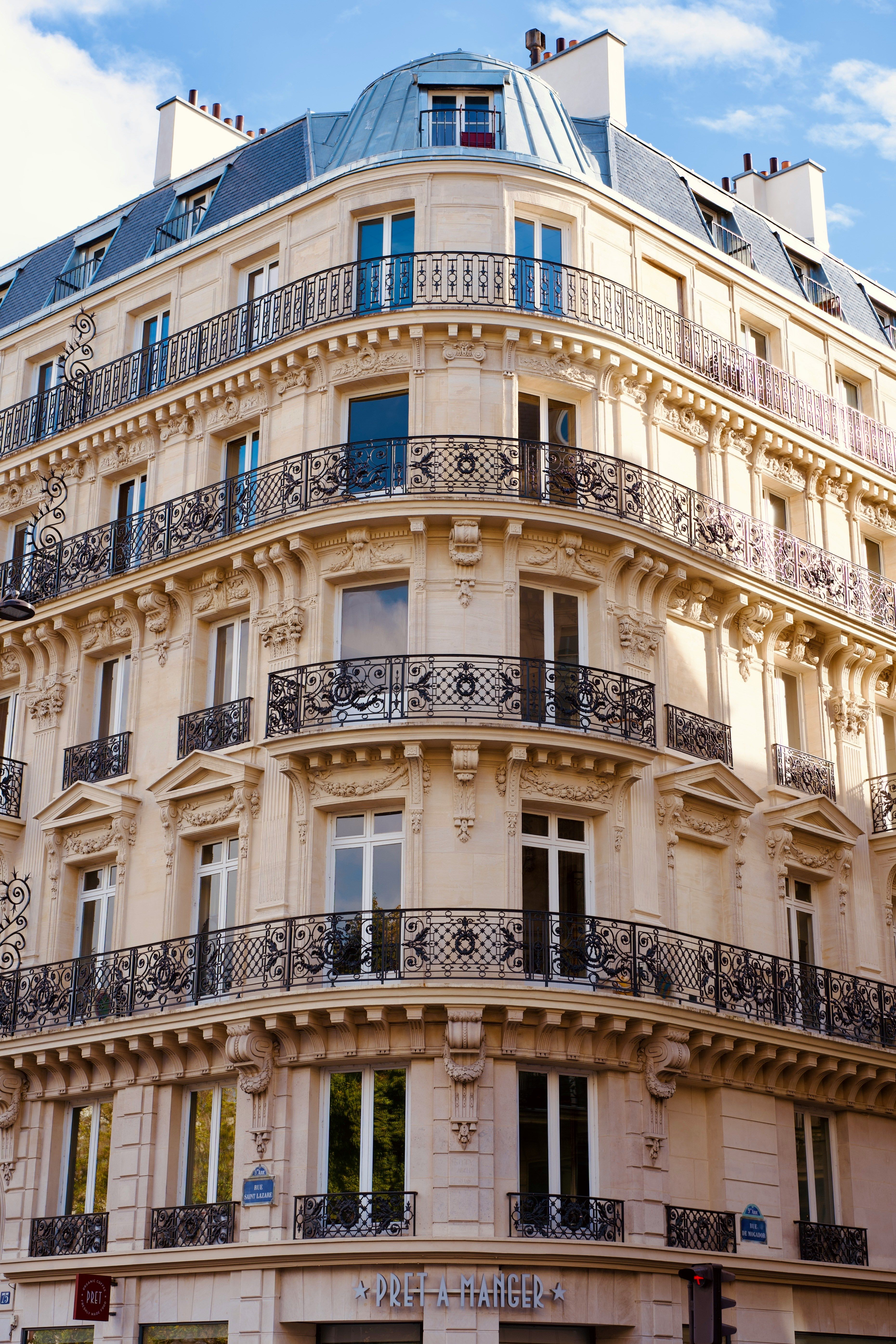 Elegant Parisian Haussmann corner building with ornate wrought-iron balconies and glass dome